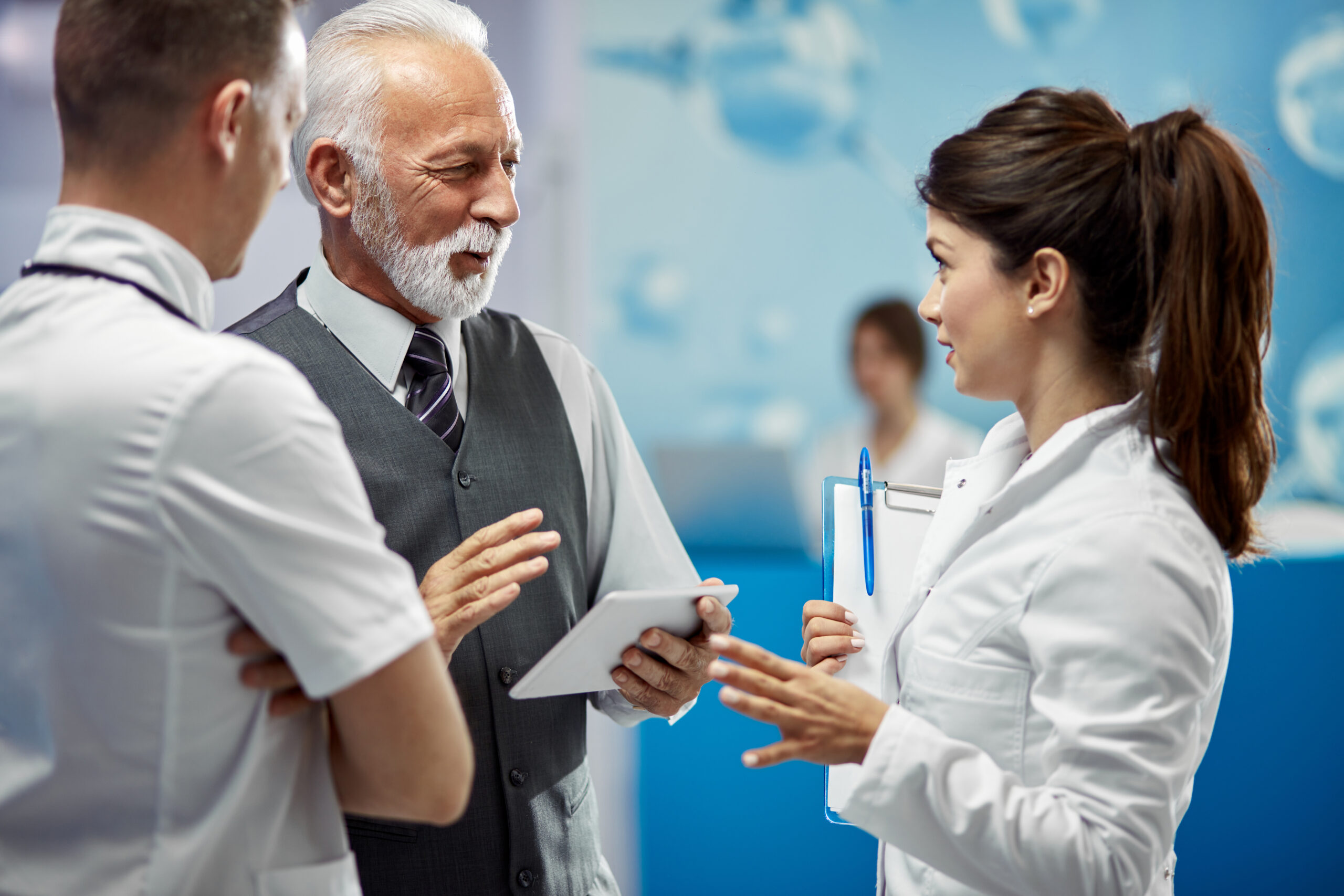 Happy senior businessman talking to doctors in hallway at the ho